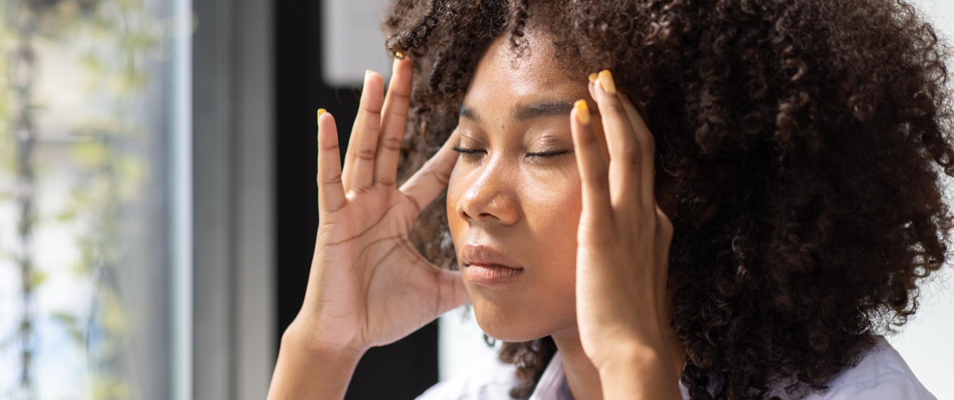 Woman with eyes closed resting her hands at her temples